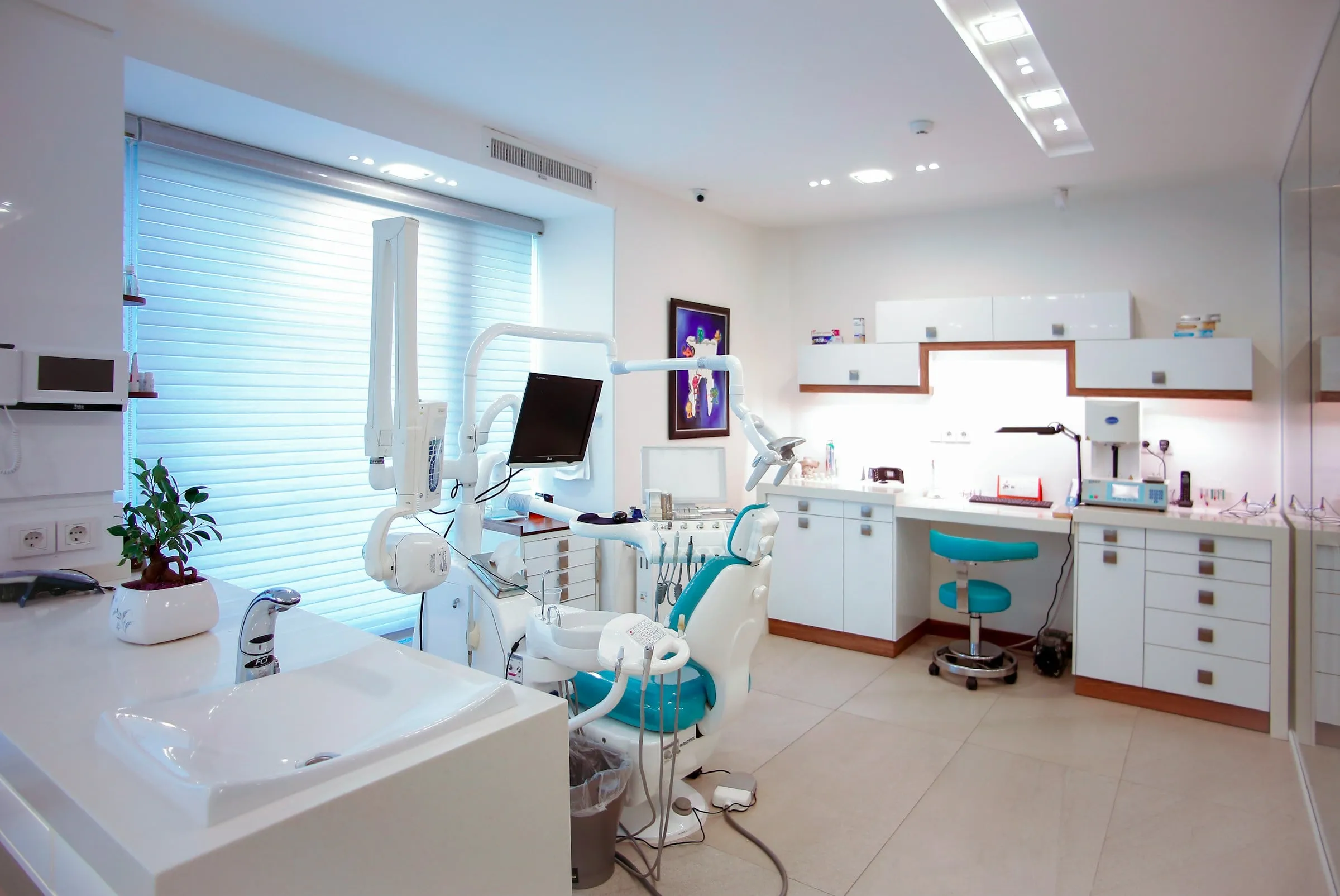 Bright polyclinic treatment room with a teal chair