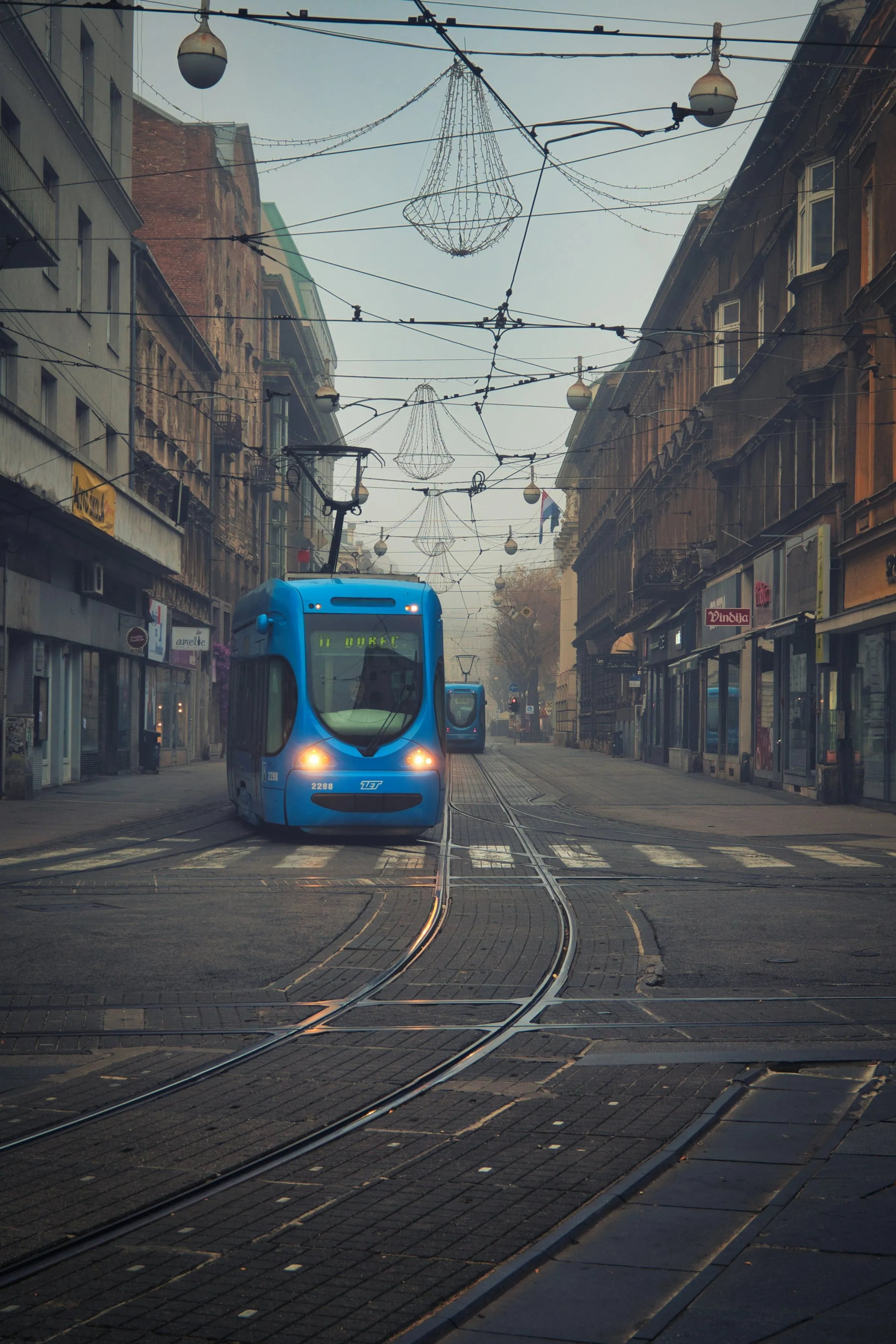 A blue Zagreb tram on a foggy street